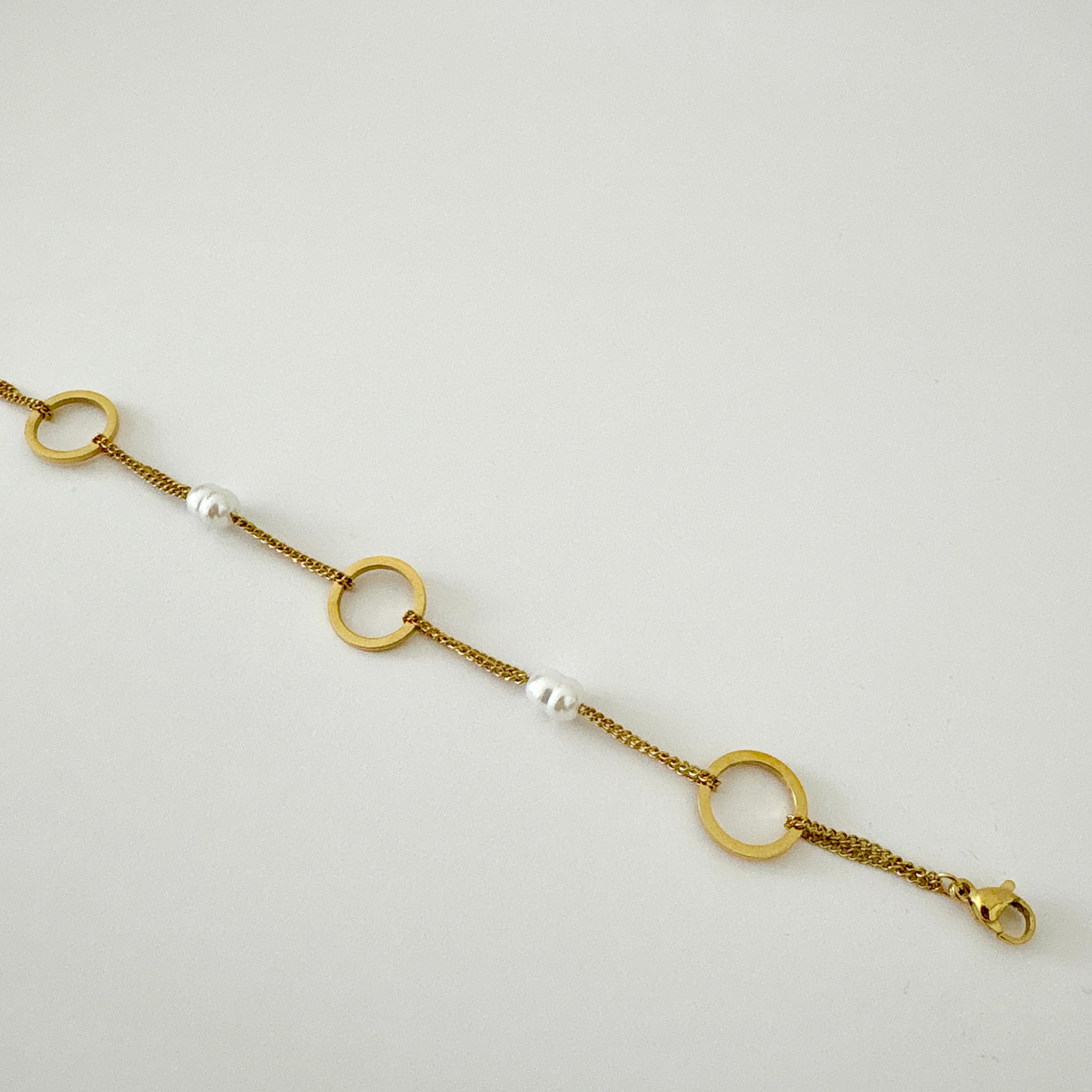 Bracelet Nora - bracelet double chaîne dorée avec anneaux ronds et perles blanches en acier inoxydable